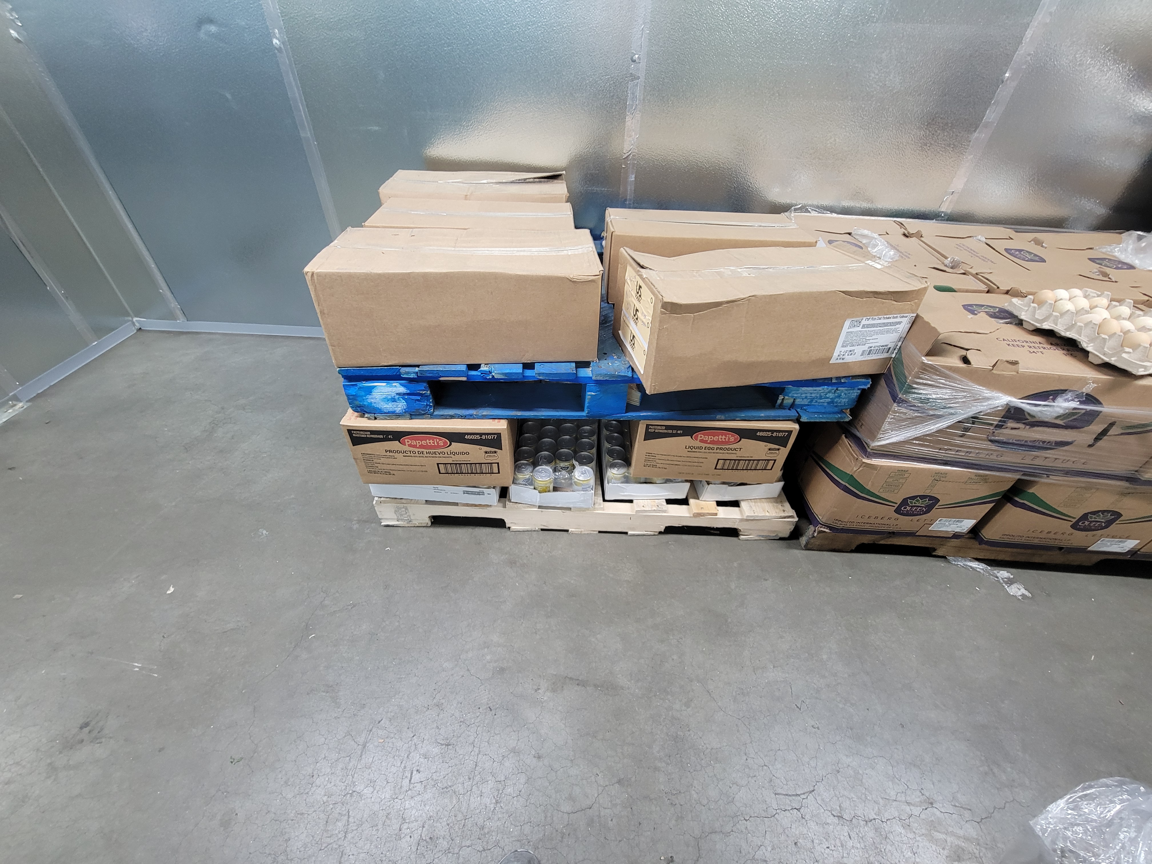 Boxes and trays of produce and drinks on pallets.